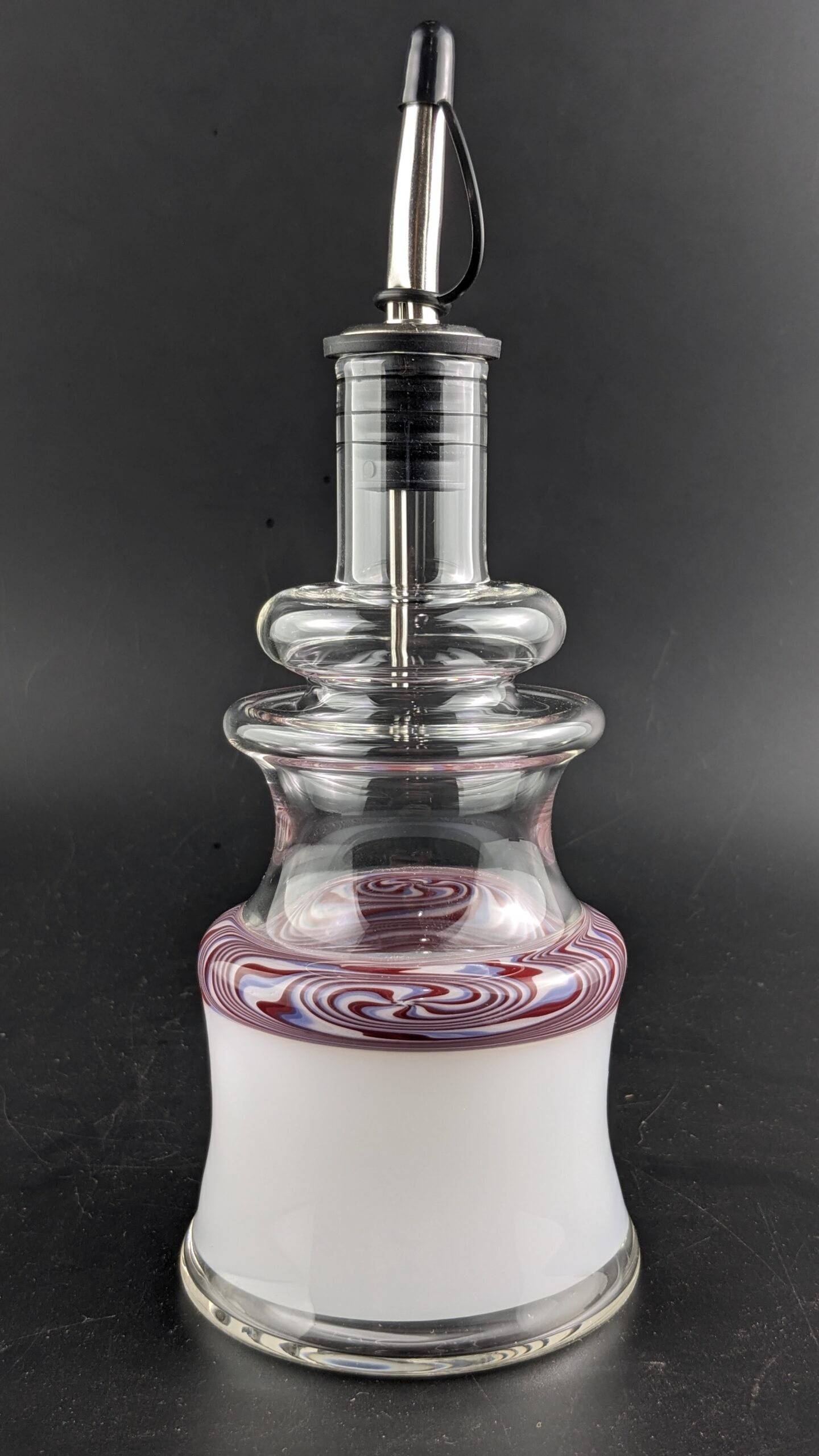 Handmade glass oil or liquor bottle with swirled red, white, and clear design, artisanal handcrafted glass vessel, decorative glass bottle for oils or spirits